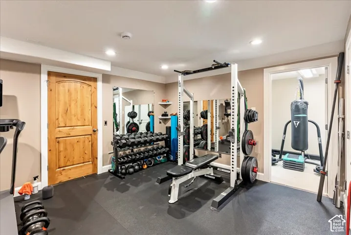 Recessed lighting, wood-finish interior door, and wall-mounted mirrors enhance this dedicated fitness space with rubber flooring