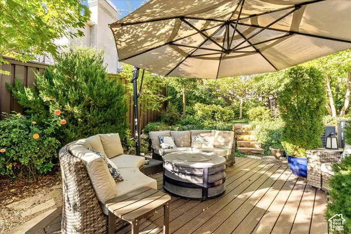 Deck with wood-finish surface, surrounded by mature landscaping, and featuring stone steps