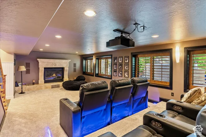Recessed lighting, a built-in fireplace with a substantial mantel, wood-finish window shutters, a ceiling-mounted projector, and carpeted flooring