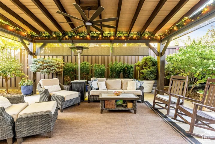 Covered patio with a slatted wood ceiling, ceiling fan, and privacy screening