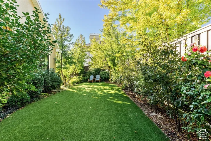 Expansive artificial turf lawn with perimeter landscaping and mature trees