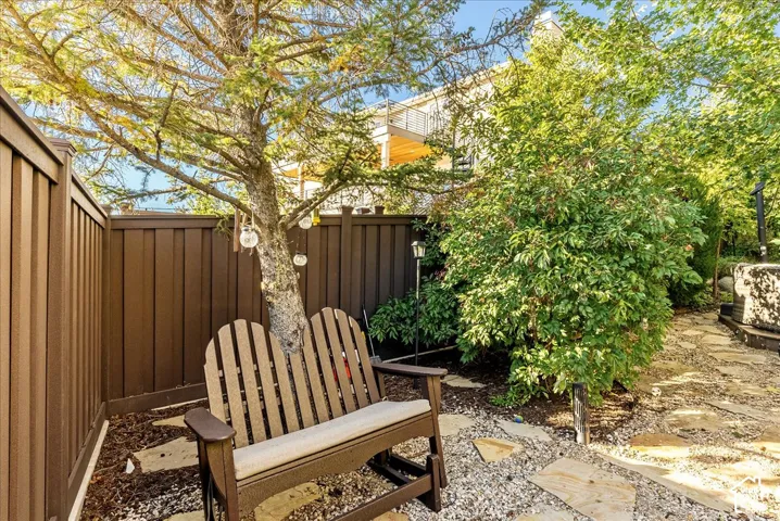 Private outdoor space featuring mature landscaping, a flagstone path, and perimeter fencing