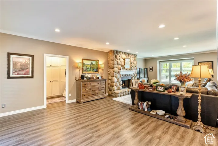 Spacious living area featuring wood-finish flooring, recessed lighting, and a stone-clad fireplace