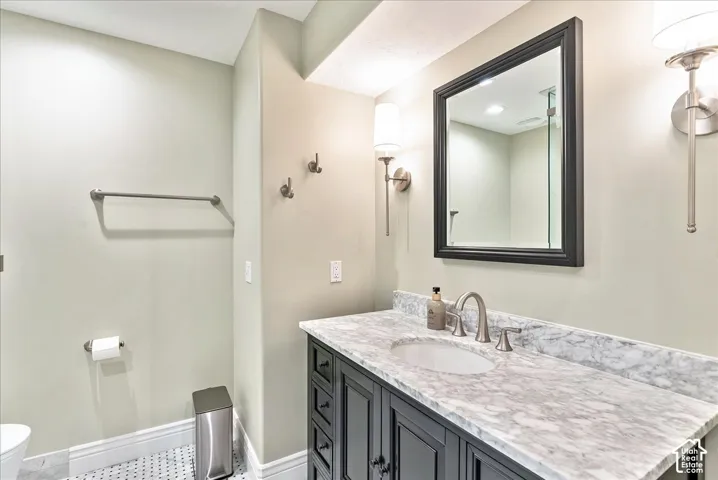 Vanity with a light-colored stone countertop, undermount sink, and a dark-framed mirror