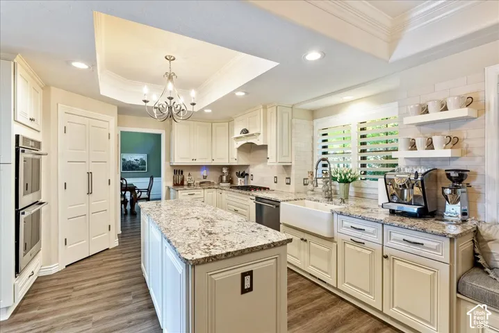 Kitchen featuring white cabinetry, wood-finish flooring, recessed lighting, and a tray ceiling with a chandelier