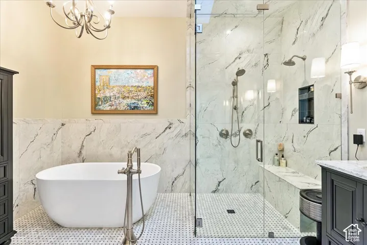 Freestanding soaking tub with floor-mounted faucet, glass-enclosed shower with multiple showerheads, marble-patterned tile, tiled shower bench, and dark wood-finish cabinetry