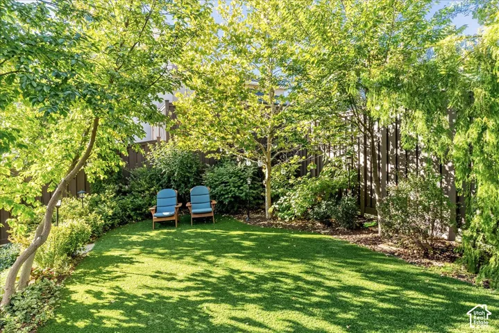 Expansive lawn with mature trees, established landscaping, and privacy fencing