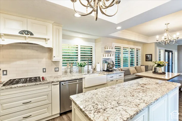 Gourmet kitchen with white cabinetry, granite countertops, subway tile backsplash, stainless steel appliances, and a farmhouse sink