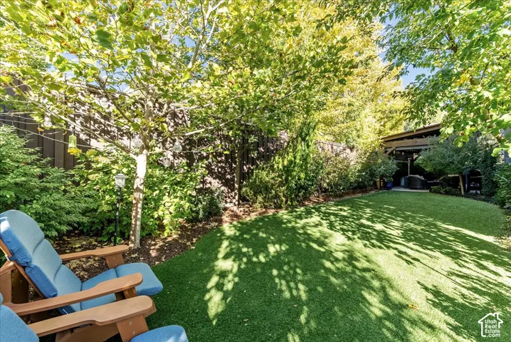 Manicured artificial turf lawn with a privacy fence and mature trees