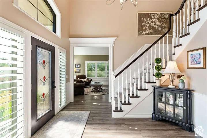 Stained glass entry door with a transom window, plantation shutters, and wood-finish flooring