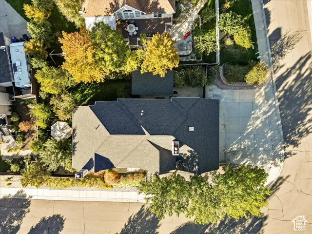 Asphalt shingle roofing, concrete driveway, and mature landscaping
