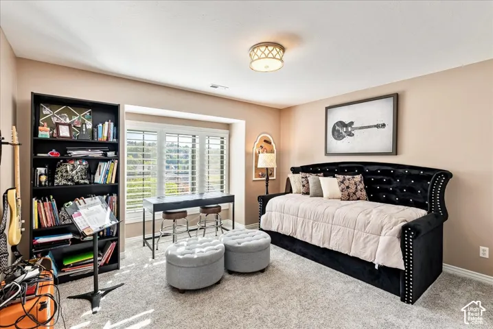 Carpeted room featuring a built-in window desk, multi-pane windows with plantation shutters, and a ceiling-mounted light fixture
