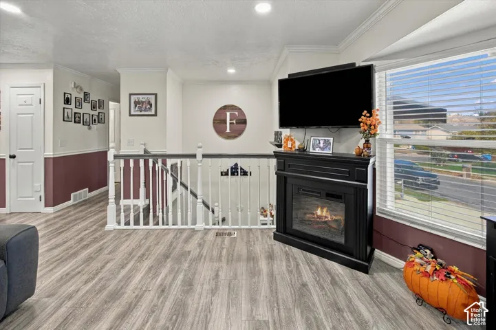 Wood-finish flooring, white interior railing, recessed lighting, and a window with blinds