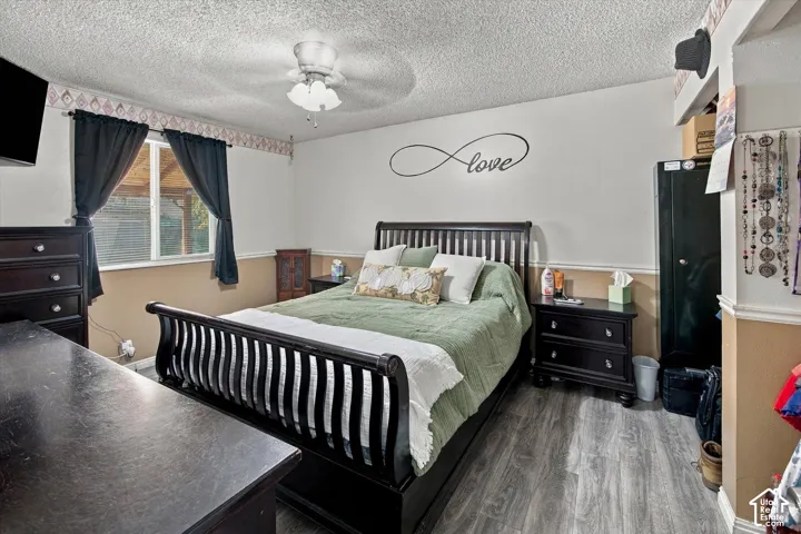 Room featuring wood-finish flooring, a ceiling fan with integrated lighting, and a window with trim