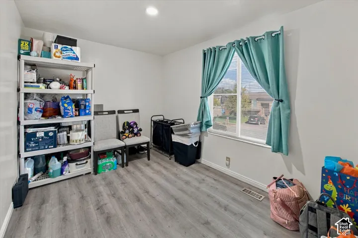 Light wood-finish flooring, white walls, and a recessed ceiling light