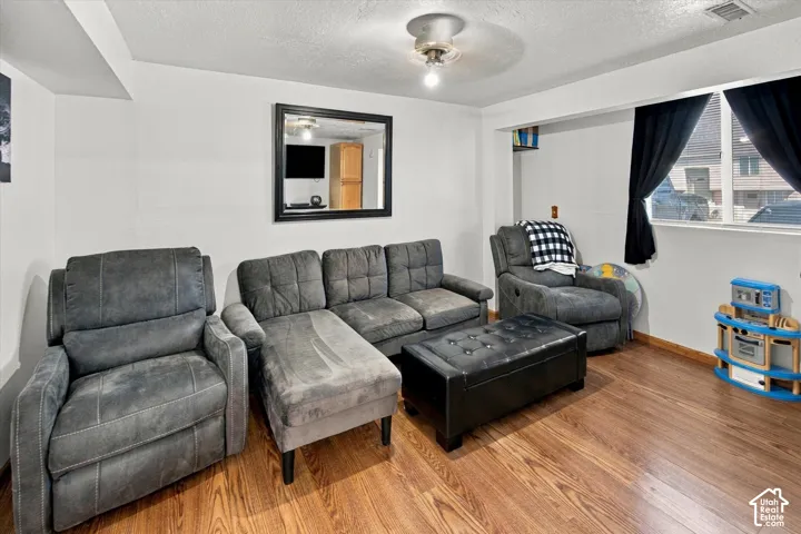 Wood-finish flooring with white walls and a ceiling fan