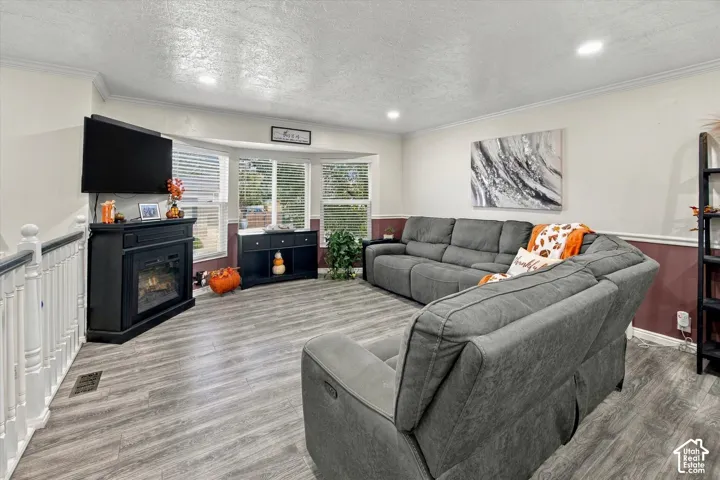 Bay windows, wood-finish flooring, crown molding, and recessed lighting