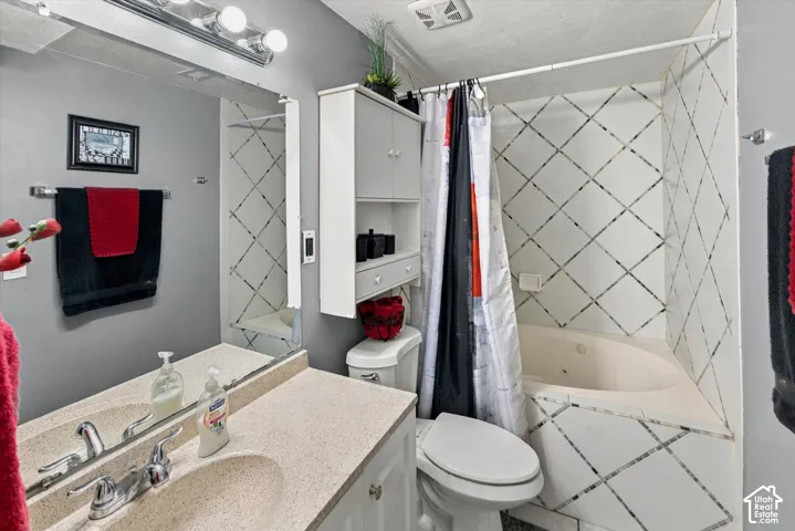 Full-width mirror, built-in wall cabinet, and a jetted tub with tile surround