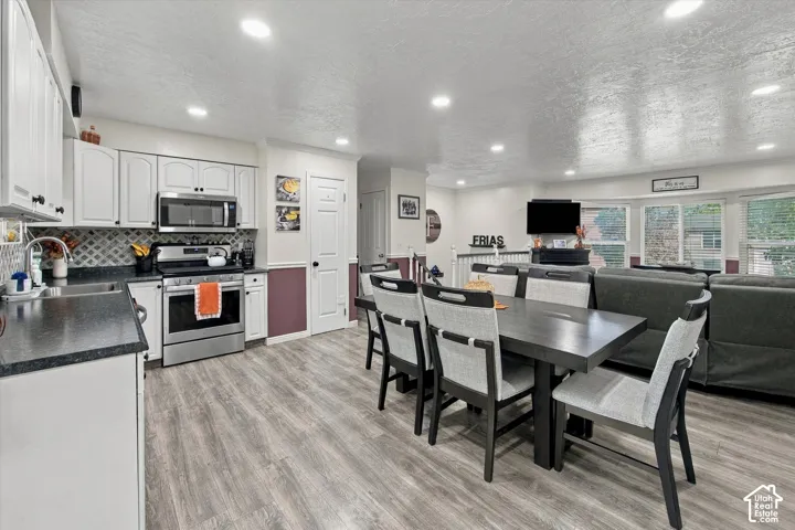 Open-concept living space with wood-finish flooring, recessed lighting, and a bay window