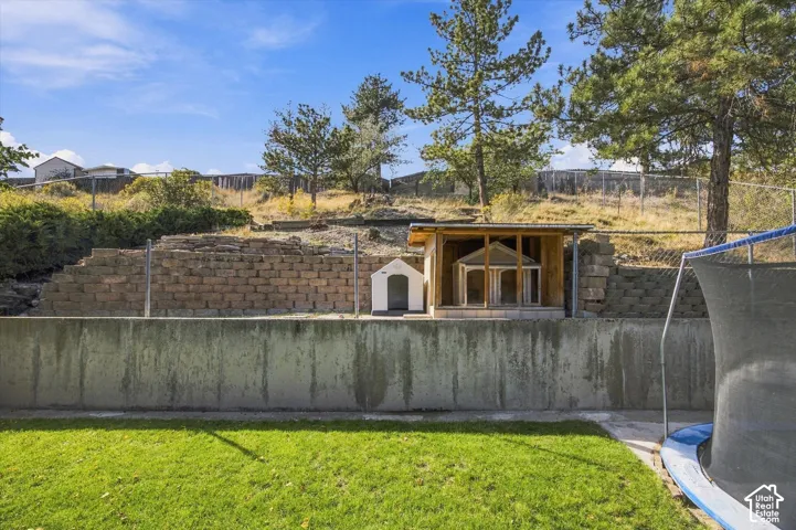 Expansive backyard with a manicured lawn, concrete retaining wall, and terraced landscaping