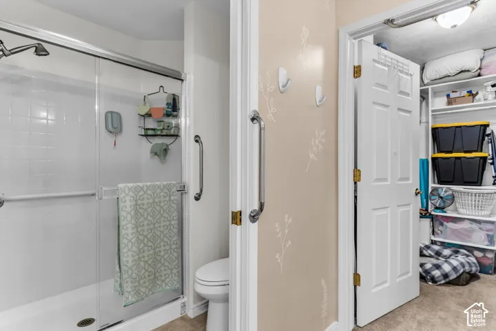 Walk-in shower with sliding glass door, white tiled surround, and integrated grab bars