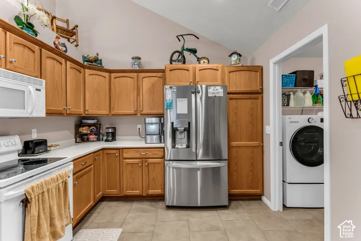 Kitchen featuring wood cabinetry, white countertops, stainless steel refrigerator, white microwave, and tile flooring