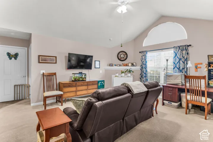 Vaulted ceiling with an arched window, ceiling fan, and carpeted flooring