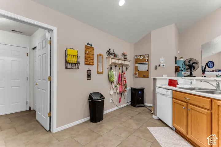 Kitchen area featuring a double basin sink, white dishwasher, and wood-finish cabinetry