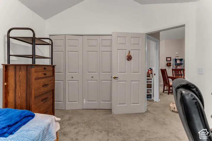Vaulted ceiling, bi-fold closet doors, interior door with paneling, carpeted flooring, and a cased opening