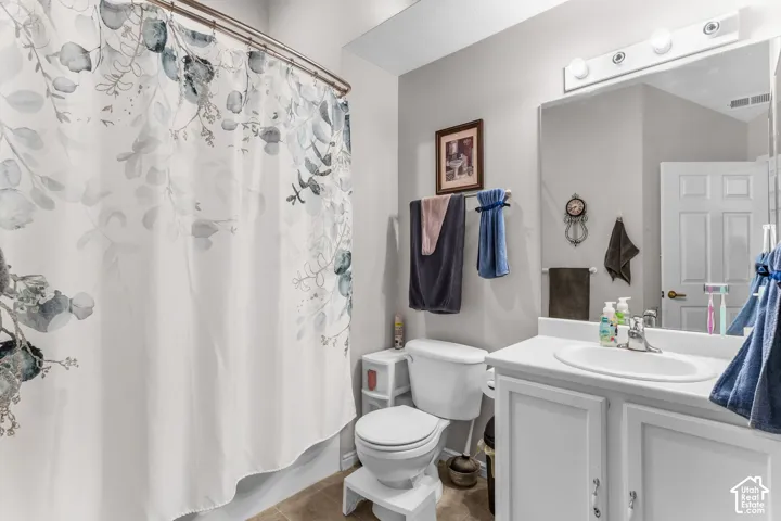 Bathroom featuring a white vanity with integrated sink, a built-in toilet, a shower/tub combination, and a large wall-mounted mirror