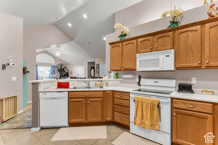 Spacious kitchen featuring warm wood cabinetry, white appliances, tile flooring, and recessed ceiling lighting