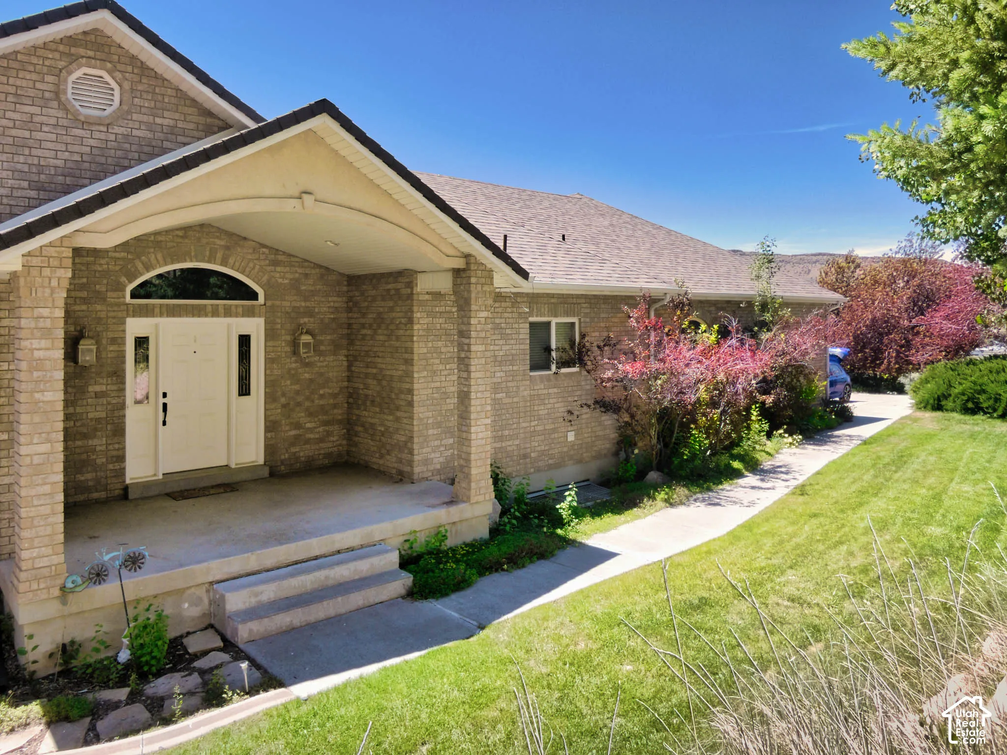 Brick exterior with a covered entry, arched transom window, and a gabled roofline
