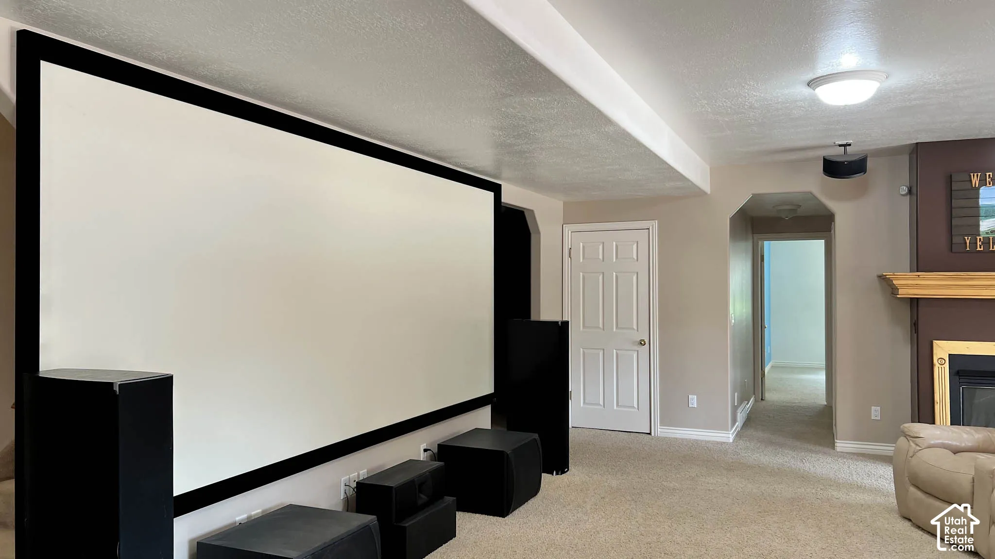 Large projection screen, recessed lighting, ceiling-mounted light fixture, arched doorway, fireplace with mantel