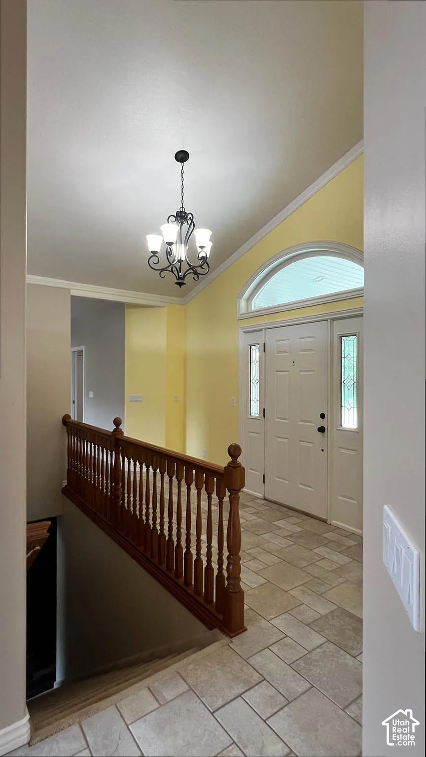 Vaulted ceiling with an ornate chandelier, arched transom window, leaded glass sidelights, and a wood-finish railing