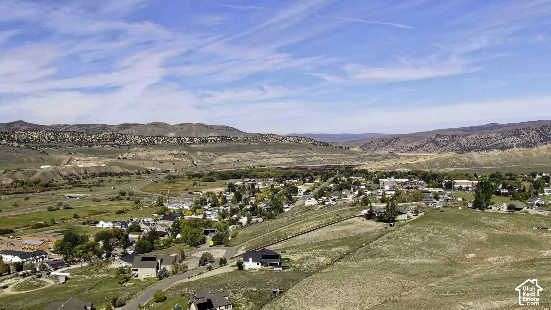 Expansive desert landscape with distant mountains, a clustered residential area, and varied terrain