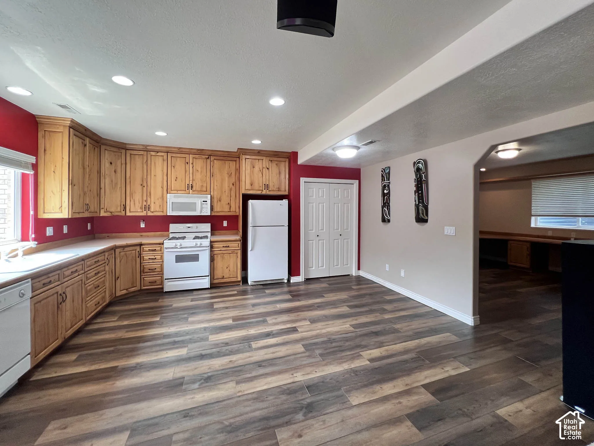 Wood-finish flooring, recessed lighting, wood cabinetry, built-in appliances, and white bi-fold closet doors