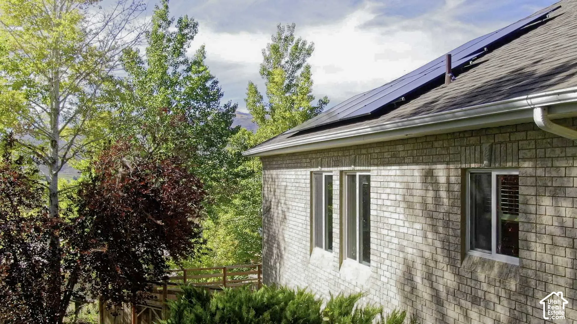 Brick exterior with multiple windows, solar panels, and a gabled roof