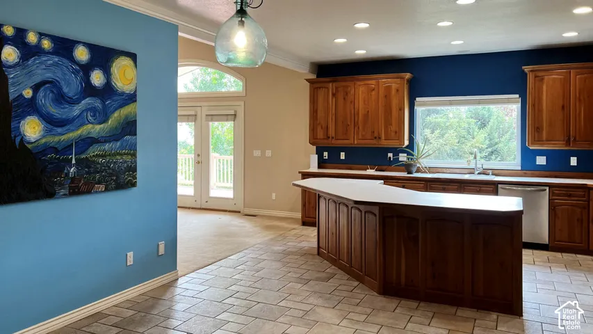 Tiled flooring in a neutral tone, custom wood cabinetry, stainless steel dishwasher, double glass-paneled doors, and a decorative overhead light fixture