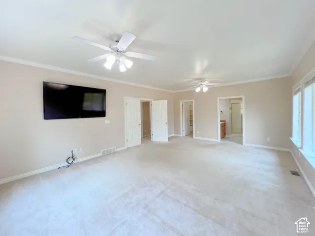 Expansive room featuring light-colored carpeting, multiple ceiling fans, and crown molding