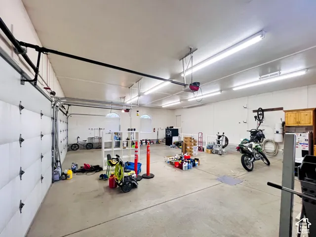 Spacious garage with multiple overhead garage doors, polished concrete flooring, overhead lighting, and built-in cabinetry