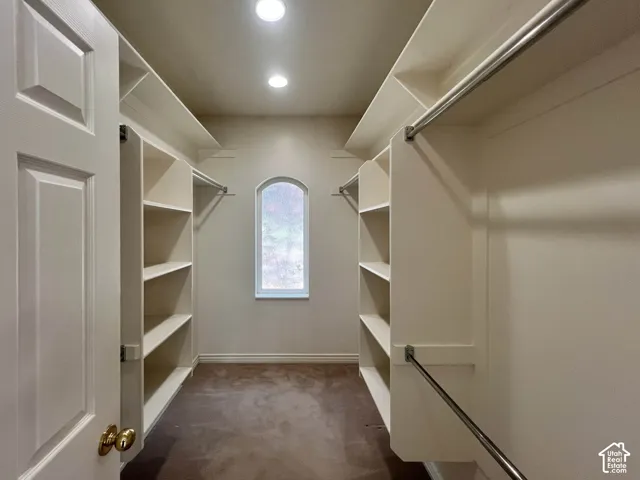 Custom built-in shelving, chrome hanging rods, an arched window, and recessed lighting