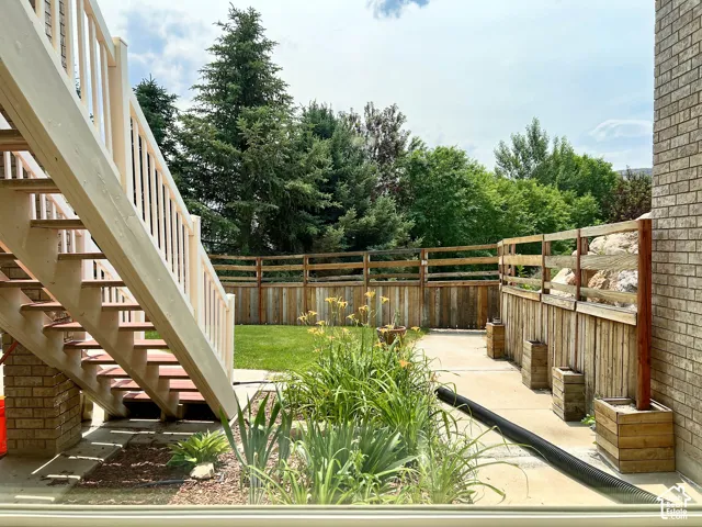 Outdoor patio with a white-railed staircase, wood-paneled fencing, and an expansive lawn