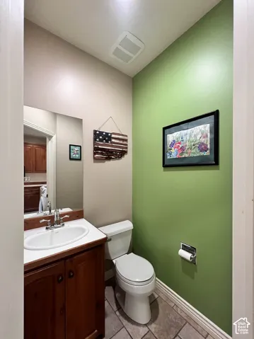 Vanity with a white oval sink and chrome faucet, wood-finish cabinetry, and tiled flooring