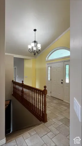 Vaulted ceiling with an ornate chandelier, arched transom window, leaded glass sidelights, and a wood-finish railing