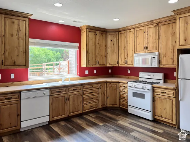 Kitchen featuring extensive wood cabinetry, wood-finish flooring, recessed lighting, and a window with a sink