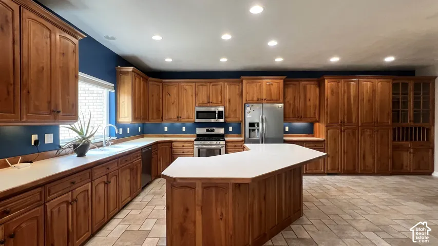 Spacious kitchen with extensive wood cabinetry, an expansive center island, stainless steel appliances, recessed lighting, and tile flooring