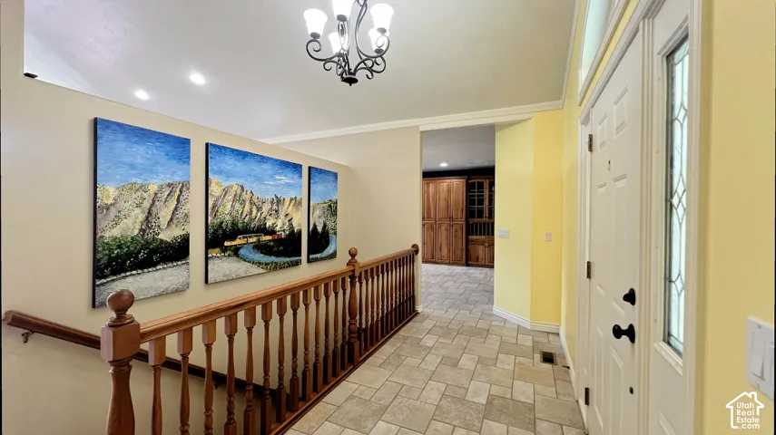 Entryway featuring a decorative transom window, tiled flooring, chandelier, and wood balusters