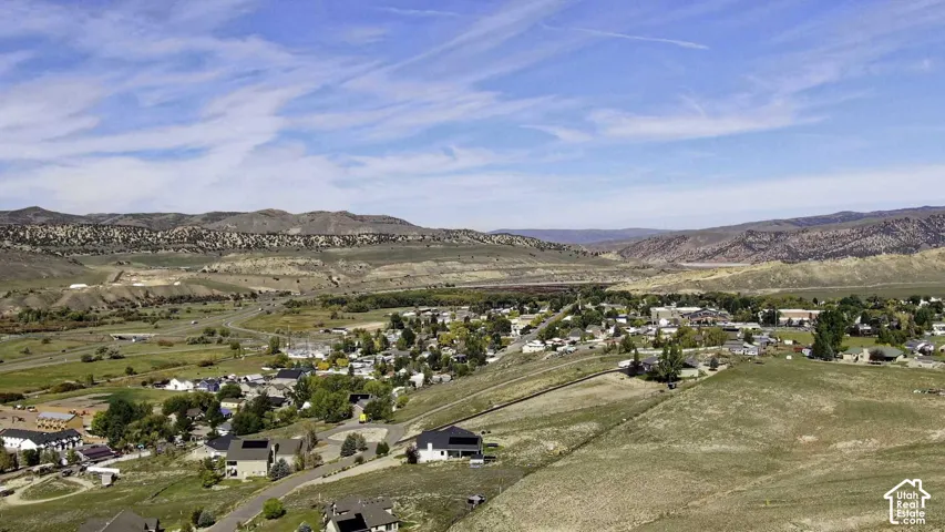 Expansive desert landscape with distant mountains, a clustered residential area, and varied terrain