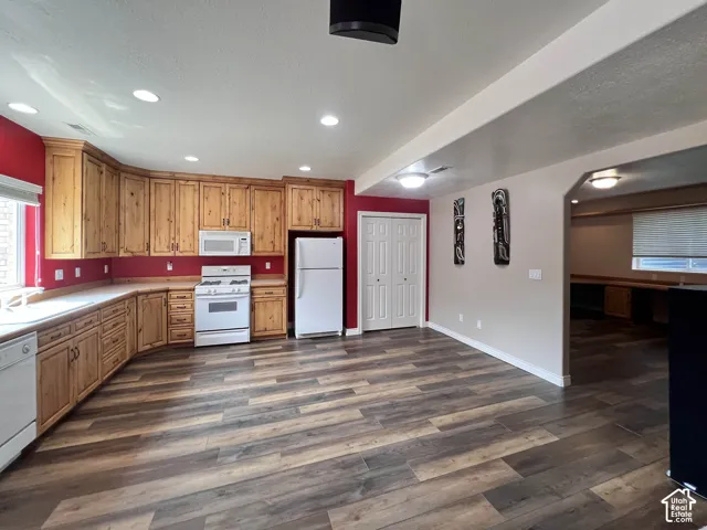 Wood-finish flooring, recessed lighting, wood cabinetry, built-in appliances, and white bi-fold closet doors