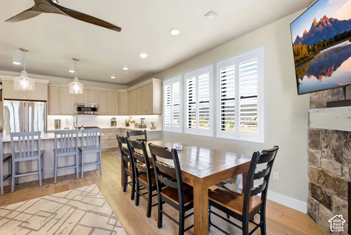 Open-concept kitchen and dining area featuring light wood-finish flooring, recessed lighting, and a ceiling fan